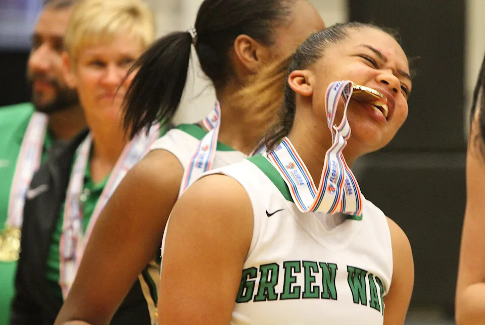 Fort Myers' Jarya Outten bites into her medal after her team beat Oakland Park Northeast in the Class 6A girls state title game on Saturday, Feb. 20, 2016, in Lakeland.