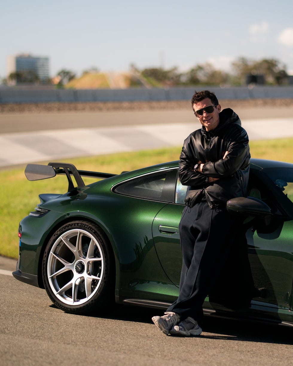 person leaning against a green sports car in an outdoor setting