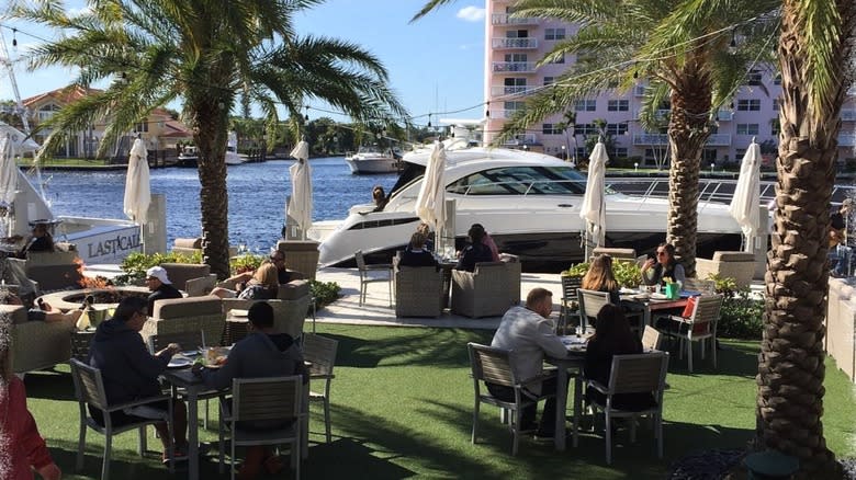 People sitting at tables at Shooters Waterfront outdoor patio with a docked boat