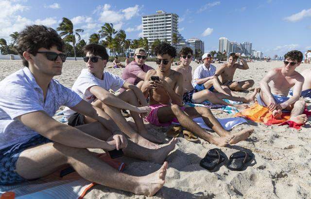 Ryan Smith, 19, a student from University of Illinois, center, sits on Las Olas Beach alongside his friends during spring break on Friday, March 20, 2026, in Fort Lauderdale, Fla.