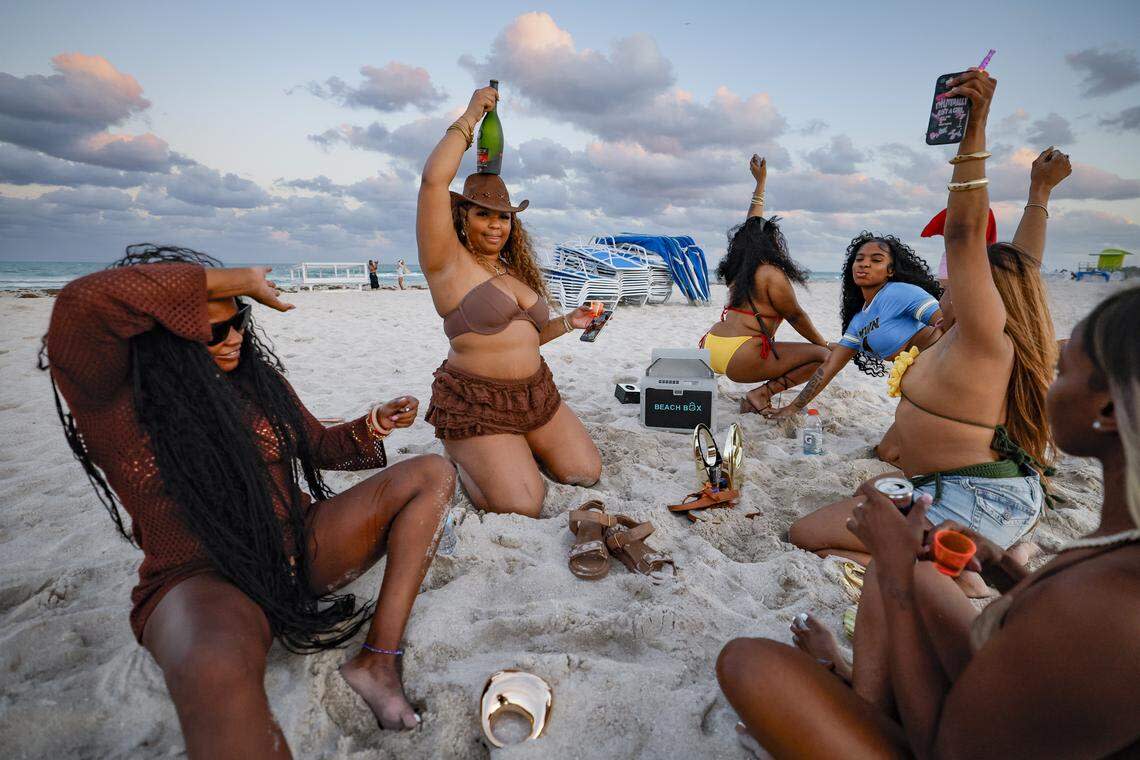 Niy Banks of Delaware balances a bottle of champagne on her head as she parties with friends on South Beach during spring break in Miami Beach, Florida on Friday, March 20, 2026.