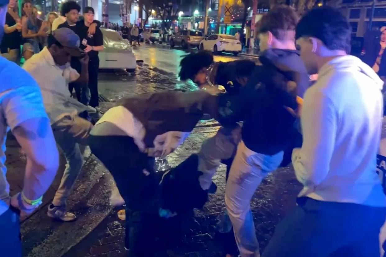 An image collage containing 1 images, Image 1 shows Spring breakers fighting on a wet city street at night