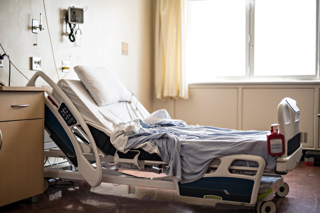 An empty hospital room with a bed and medical equipment.