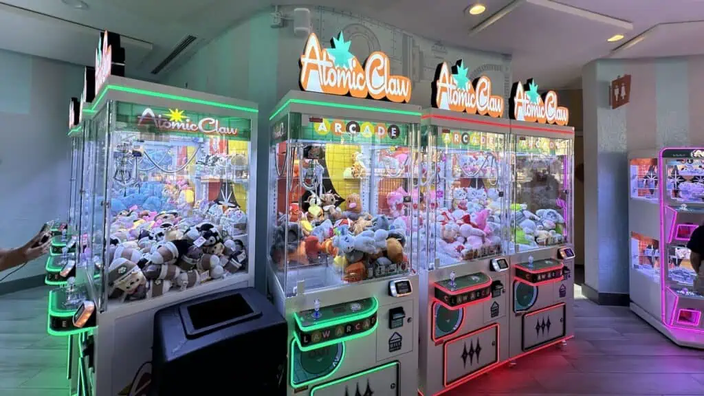 inside a claw machine aracade. 3 different machines filled with plush prizes are on view