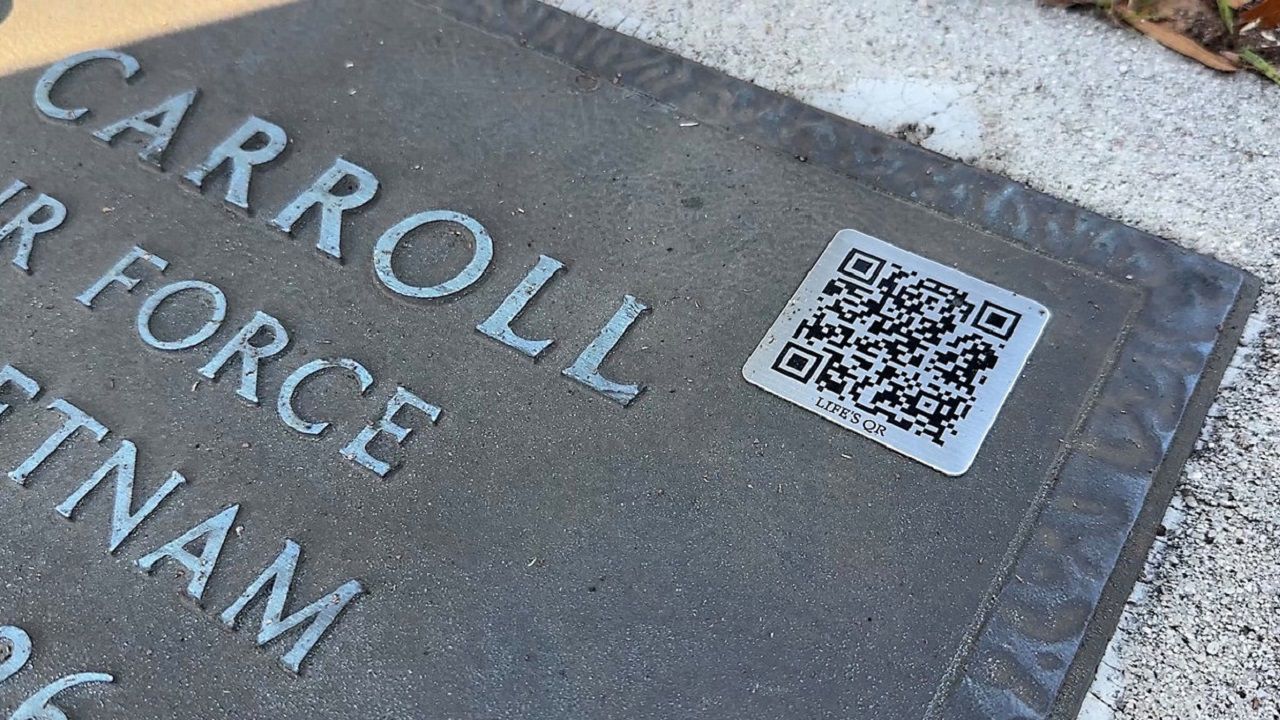 At Lutz Cemetery, some graves have a stainless steel QR code affixed to the gravestone. Visitors to the cemetery can use that QR code to view the biography through a company called Life’s QR. (Spectrum News/Jeff Butera)