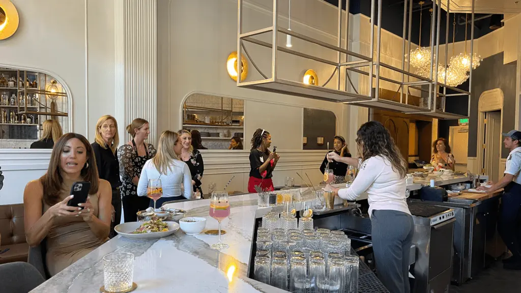 Interior champagne bar. White marble countertops and golden exposed lights hang from the ceiling.