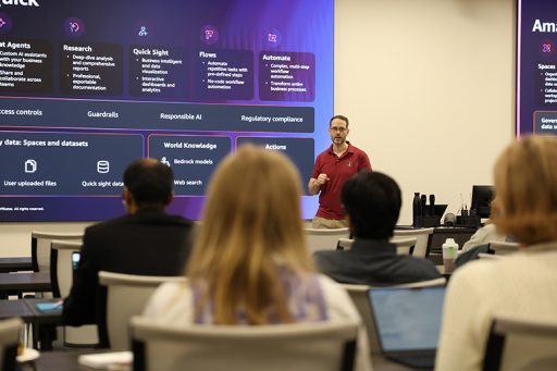 A man in a garnet polo shirt presents information about cloud computing to a group of people.