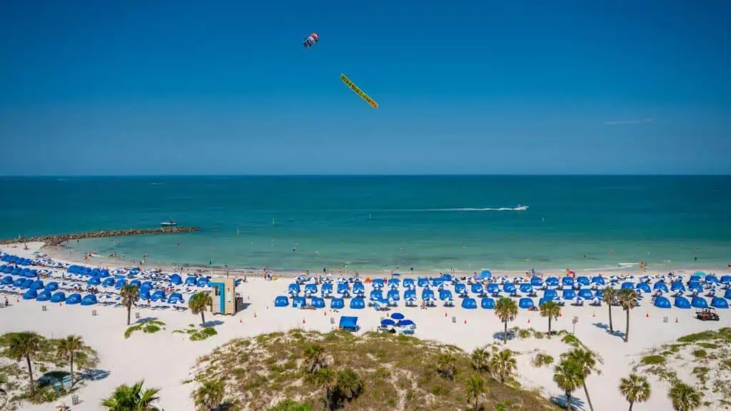aerial view of clearwater beach. many rows of blue cabananas are set up on the white sand beach