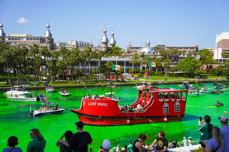 he Lost Pearl pirate ship sails on the bright green dyed Hillsborough River in downtown Tampa during the Mayor’s River O'Green St. Patrick's Day festival, with the University of Tampa minarets in the background.