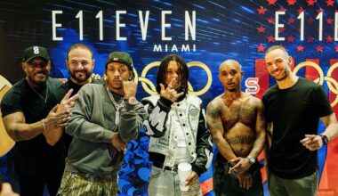 photo of six men posing together in front of a step-and-repeat showing a logo for E11even Miami