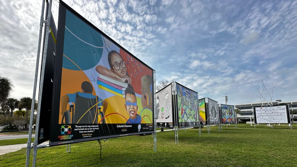 multiple artist banners set up along a walkway at a waterfront park