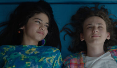 Still from the film 'Ethan Bloom' showing an overhead view of a young boy and older girl lying down. The boy looks up at the sky and the girl looks at the boy