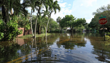 An intersection in a residential neighborhood flooded with rainwater.