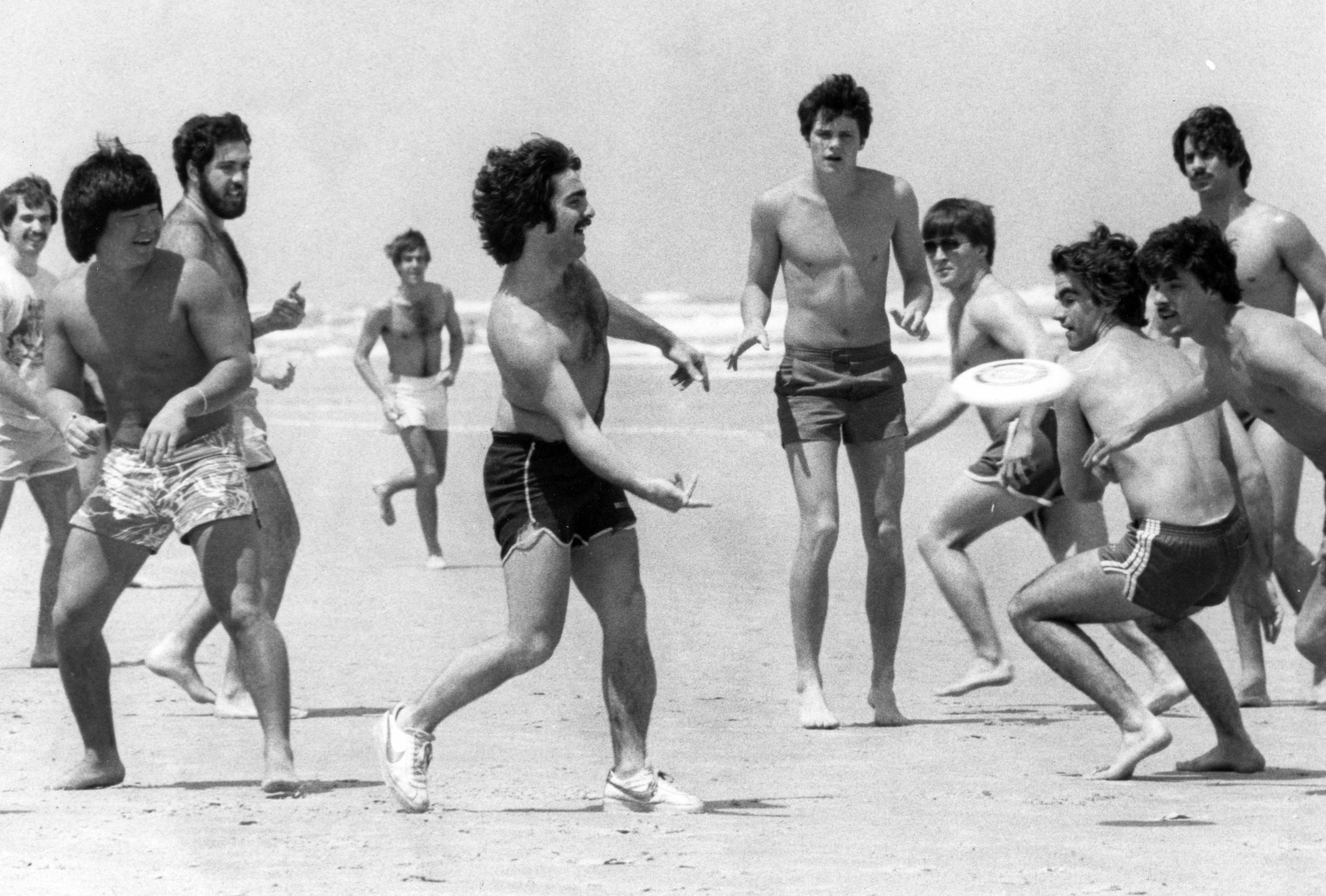 A group of college students play frisbee football on Daytona...
