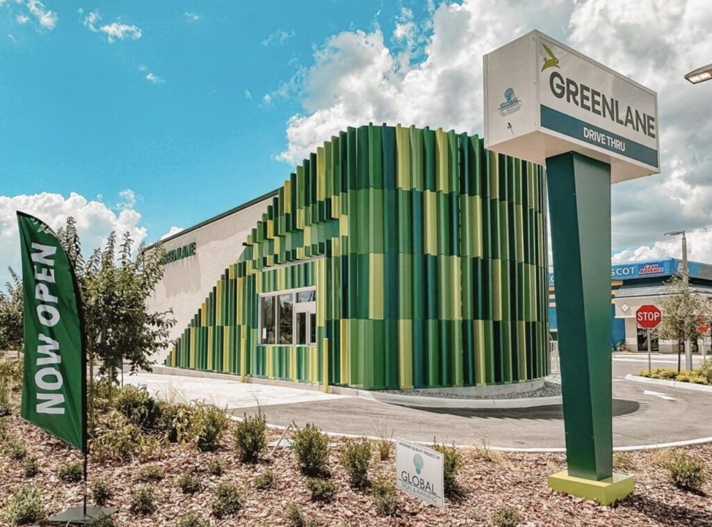 The exterior of a newly opened Greenlane Drive Thru restaurant, featuring a distinctive building design with vertical green and yellow panels.