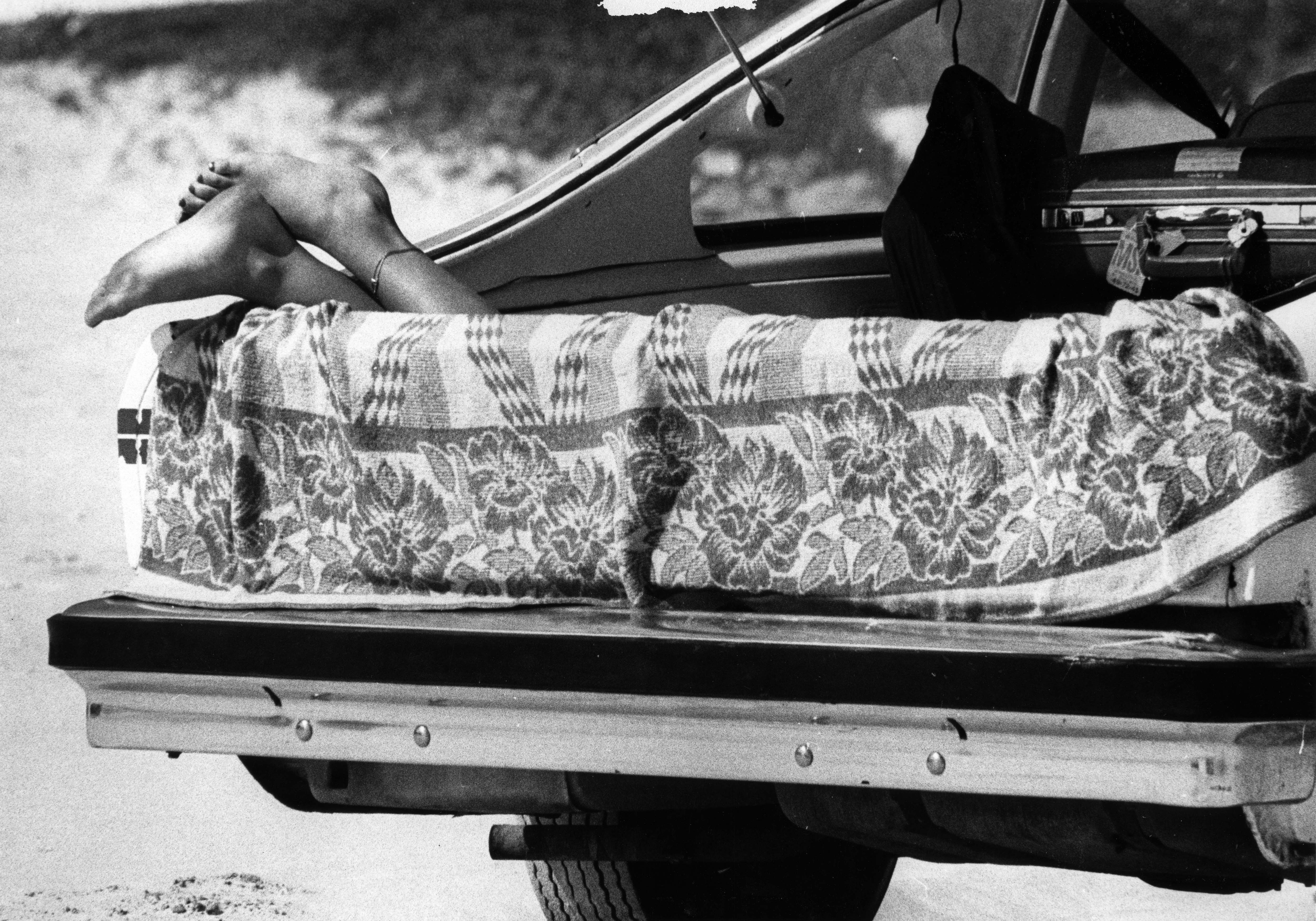 A woman naps in her hatchback on Daytona Beach during...