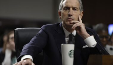 photo of Starbucks CEO testifying in front of a senate committee on Capitol Hill. An out-of-focus Starbucks thermos is in front of him on the desk.