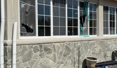 Two outer windows have torn screens in the back yard of a house with a light colored stone finishes in a house in Longwood. (Spectrum News 13)