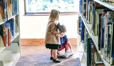 Two children stand among stacks of books