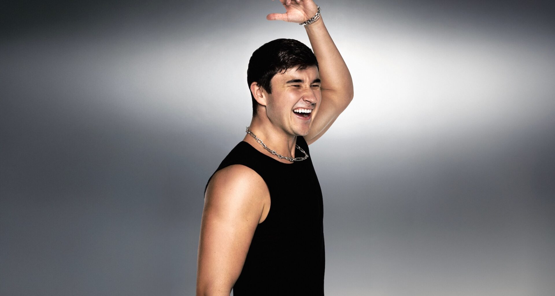 Photo of a man with a sleeveless black shirt raising a hand in the air.