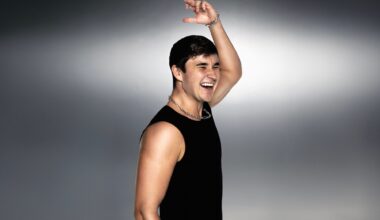 Photo of a man with a sleeveless black shirt raising a hand in the air.
