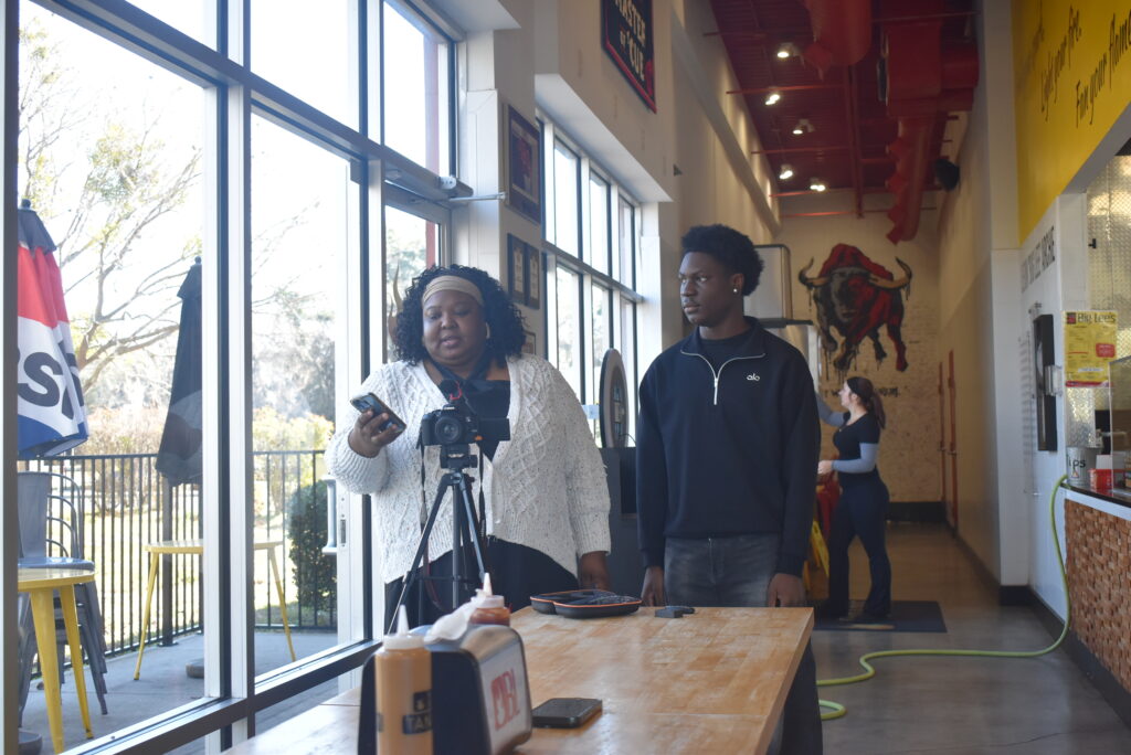 La Sana Groome and Hakeem Norgaisse set up a camera and recording equipment to interview Rashad Jones, owner of Big Lee's BBQ.