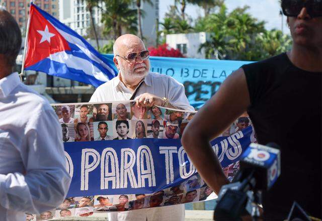 In the center Guz Garcia holds a banner of the many Cuban activists who have been persecuted by the regime as Movimiento Democracia, along with the Movement of Opponents for a New Republic (MONR) and several notable activists, held a press conference to discuss the denied Right to Return for Cuban exiles to their homeland. The event focused on the civic response to the upcoming “Our America Convoy,” which is organized by Mariela Castro and groups aligned with the Cuban regime on Monday, March 16, 2026, in Miami, Florida. The convoy is scheduled to depart from Mexico and arrive at the Havana Malecón on March 21, 2026.