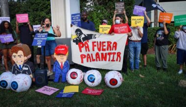 Organizer Cathy Carrillo stands at the makeshift podium to give her remarks as a small group of gathered around the mall entrance, wielding bright signs that conveyed messages calling for increased accountability and transparency from the tech giant on Tuesday, March 3, 2026 at the entrance of Aventura Mall in Aventura, Florida.