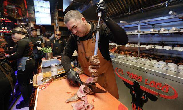 Grill Master Ramon Rodriguez cuts meat in the kitchen at El Toro Loco Steakhouse restaurant in Little Havana. 