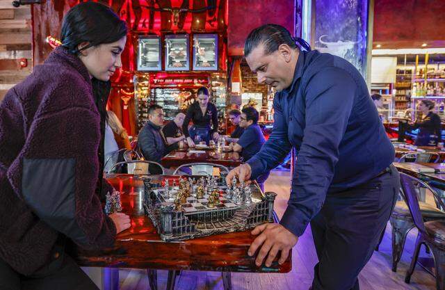 Gaby Quintero plays chess with owner Aldo Espinosa at El Toro Loco Steakhouse in Little Havana.