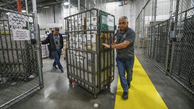 Engelbert Asiatico and fellow employees prepare to load carts full of vote-by-mail ballots onto a waiting USPS truck in the loading bay at the Miami-Dade Supervisor of Elections Office in Doral, Florida, on Thursday, March 19, 2026.