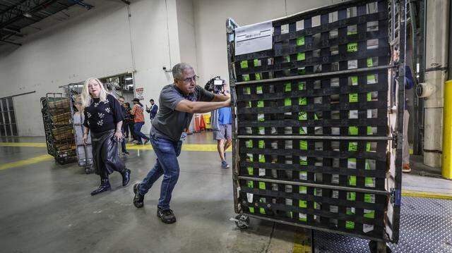 Miami-Dade Supervisor of Elections Alina Garcia watches Engelbert Asiatico loads a cart full of vote-by-mail ballots onto a waiting USPS truck in the loading bay at the Miami-Dade Supervisor of Elections Office in Doral, Florida, on Thursday, March 19, 2026. The ballots will be delivered to voters for the upcoming Coral Gables election.