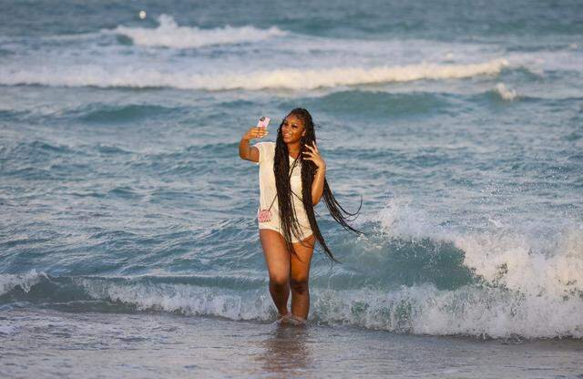 Lea Smith of South Carolina takes a selfie on the shores of South Beach during spring break in Miami Beach, Florida, on Friday, March 20, 2026.