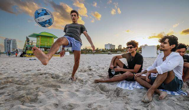 Omar Mutau kicks a soccer ball as fellow New York University students Zain Smith and Abdullah Duli, seen left to right, enjoy spring break on South Beach, in Miami Beach, Florida on Friday, March 20, 2026.