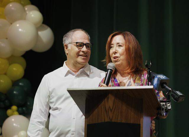 Pam Kirtman, right, speaks to the senior class next to her husband, Jay, founders of Becca's Closet, named after their late daughter Rebecca, during a ceremony with the senior class announcing that Becca's Closet and Macy's donated $65,000 so that prom would be free for students on Thursday, March 26, 2026, at Nova High School in Davie, Fla. “It's not about a dress, it's about coming together,” reflected Jay. “Rebecca only went to one homecoming and every girl I give a dress to warms my heart.”