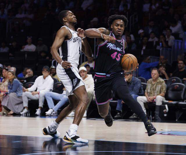 Miami Heat guard Davion Mitchell (45) dribbles around San Antonio Spurs guard De'aaron Fox (4) during the first half of the game on Monday, March 23, 2026, at the Kaseya Center in downtown Miami, Fla. 