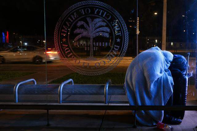 A man experiencing homelessness sleeps at a bus stop near Lummus Park in downtown Miami during the Homeless Trust's biannual Homeless Census on Thursday, Jan. 22, 2026.