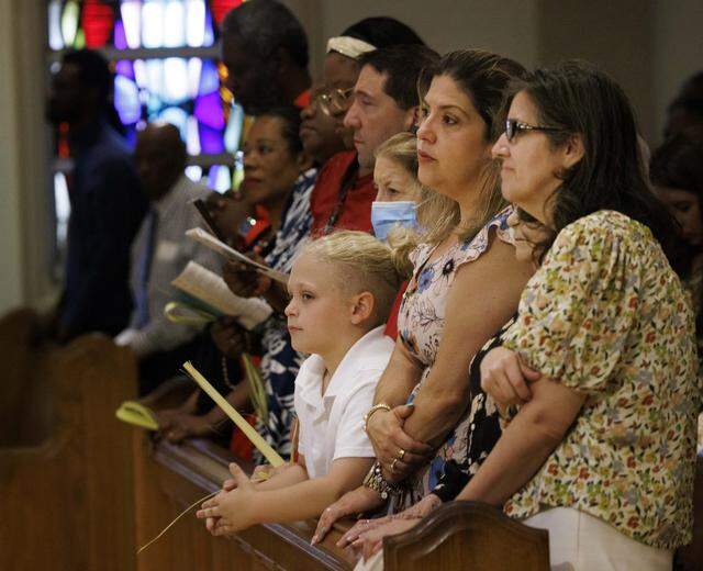 Parishioners hold palms and listen to scripture during Palm Sunday Mass on Sunday, March 29, 2026, at the Cathedral of St. Mary in Miami, Fla. The service began with the traditional blessing of the palms outside the cathedral followed by Mass.