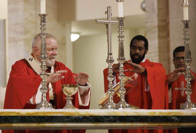 Archbishop Thomas Wenski, left, and Reverend Jeremy Lully pray over the blood of Christ during Palm Sunday Mass on Sunday, March 29, 2026, at the Cathedral of St. Mary in Miami, Fla. The service began with the traditional blessing of the palms outside the cathedral followed by Mass.