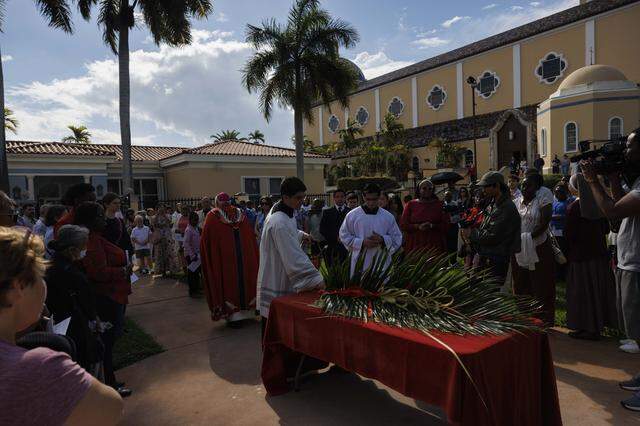 People reflect during the traditional blessing of the palms outside the cathedral before Palm Sunday Mass on Sunday, March 29, 2026, at the Cathedral of St. Mary in Miami, Fla. 