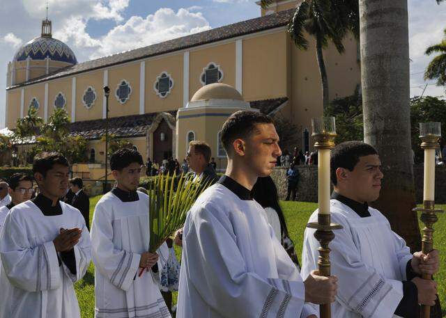 Alter servers process past the crowd towards the cathedral after the traditional blessing of the palms before Palm Sunday Mass on Sunday, March 29, 2026, at the Cathedral of St. Mary in Miami, Fla.