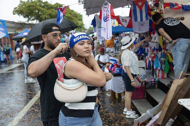 Neftaly Luna help his girlfriend Heslin Lopez, both of Nicaragua origin, with the scarf during Calle Ocho festival on Sunday, March 15, 2026 in Little Havana. Andrew Uloza / for Miami Herald