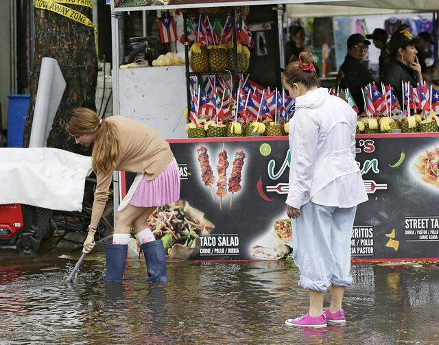 The vendors try to unclog the rain drain on SW 8 street in Little Havana during Calle Ocho festival on Sunday, March 15, 2026. Andrew Uloza / for Miami Herald
