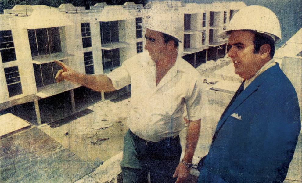 Honoring José Milton: A visionary who helped build South Florida and the communities within it 2 Two men wearing white construction hard hats stand at a building site, looking over a partially completed multi-story structure.