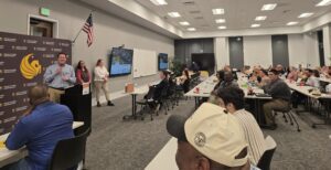 a man speaking to a large room including students