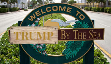 A sign of Lauderdale by the Sea where the Lauderdale is covered by a illustration of a piece wood that says, "Trump" in gold.