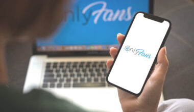 A photo of a phone with the "OnlyFans" logo on the screen alongside a laptop with the "OnlyFans" logo on the screen.