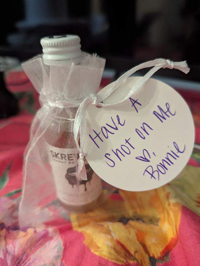 ‘Have a shot on me,’ a note on a bottle of peanut butter whiskey says. The shots were given out to attendees at the funeral of Bonnie Bouffard.