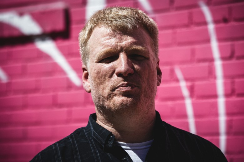 St. Pete Razing founder Cedric Harris stands in front of a pink-painted brick wall with white mural markings in downtown St. Petersburg, part of the controversial 'Art is the ultimate luxury' installation at the site of future luxury condos.
