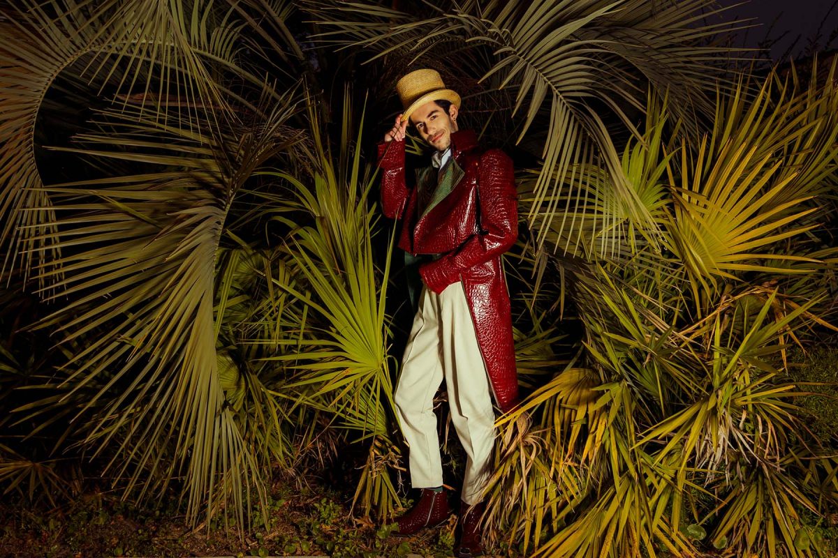 A ringmaster stands between palm fronds